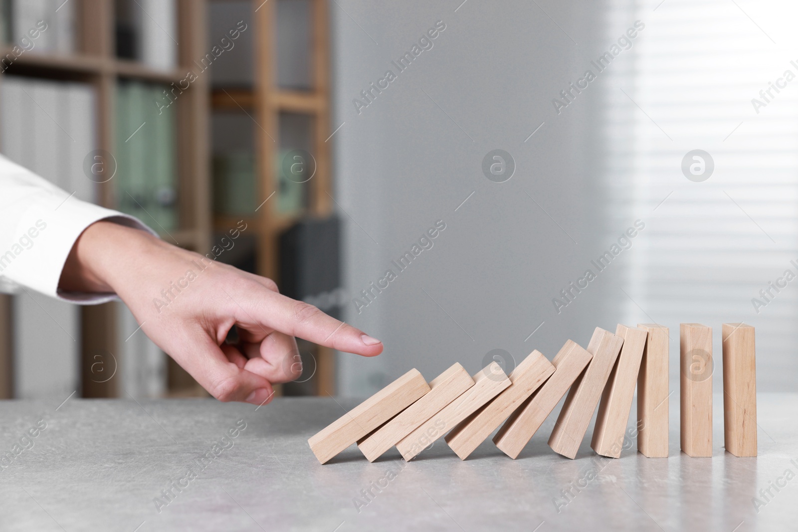 Photo of Domino effect. Man pushing wooden blocks at table, closeup