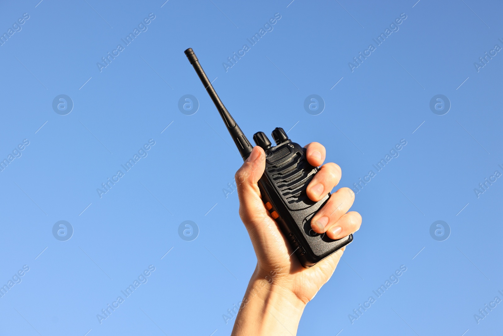 Photo of Woman with walkie talkie against blue sky outdoors, closeup