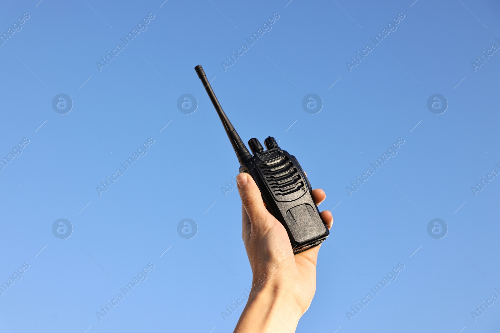 Photo of Woman with walkie talkie against blue sky outdoors, closeup