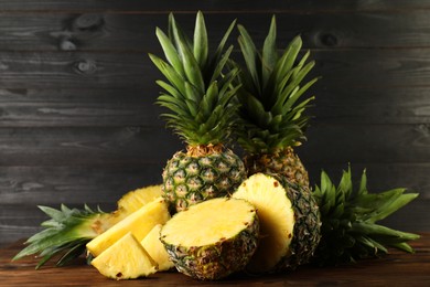 Whole and cut ripe pineapples on wooden table