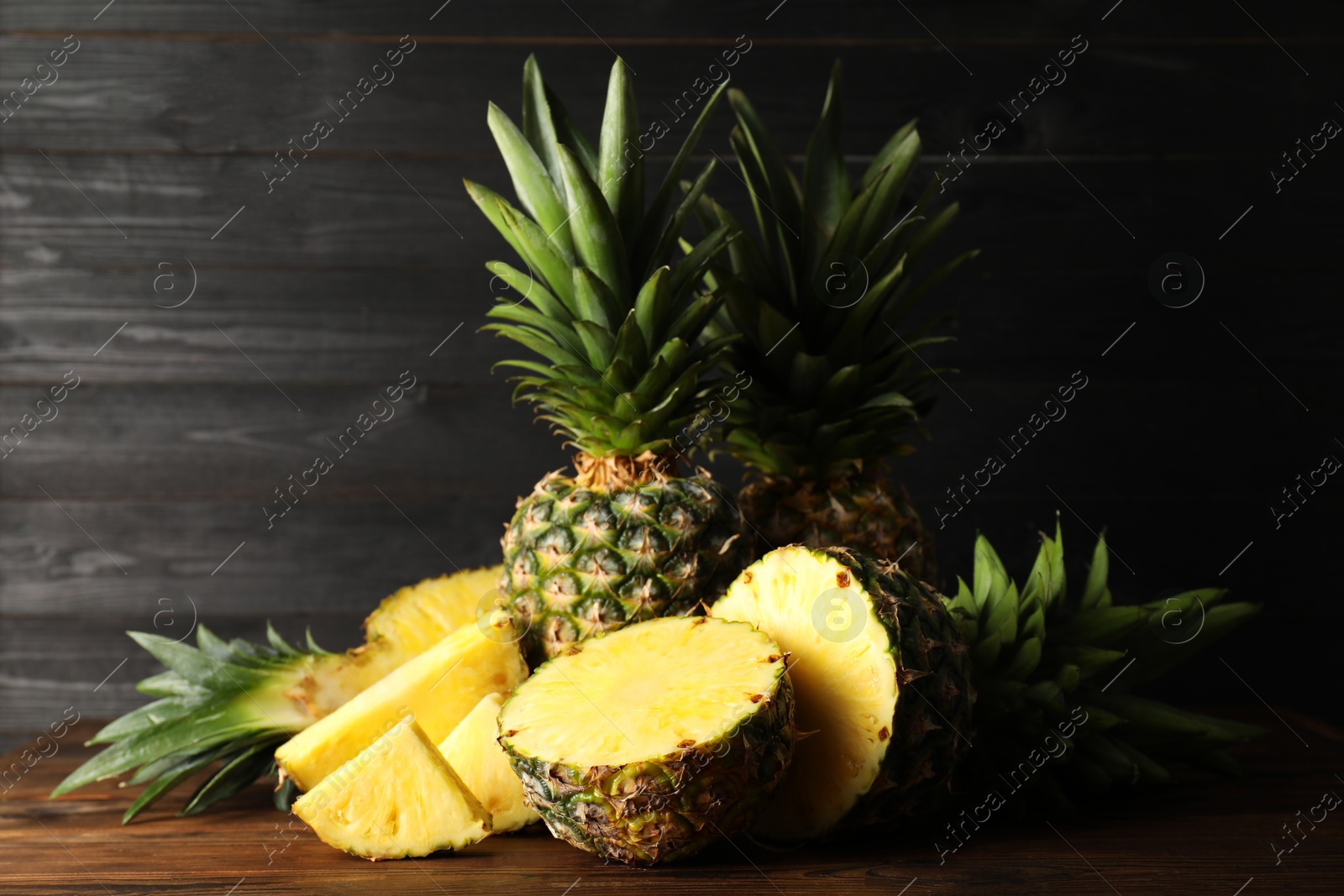 Photo of Whole and cut ripe pineapples on wooden table