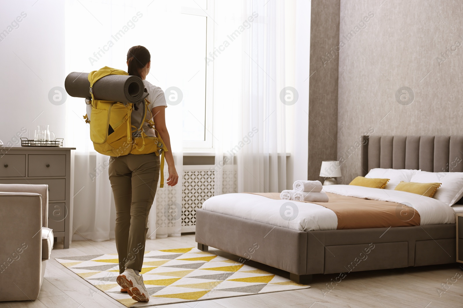 Photo of Traveller with backpack in hotel room, back view