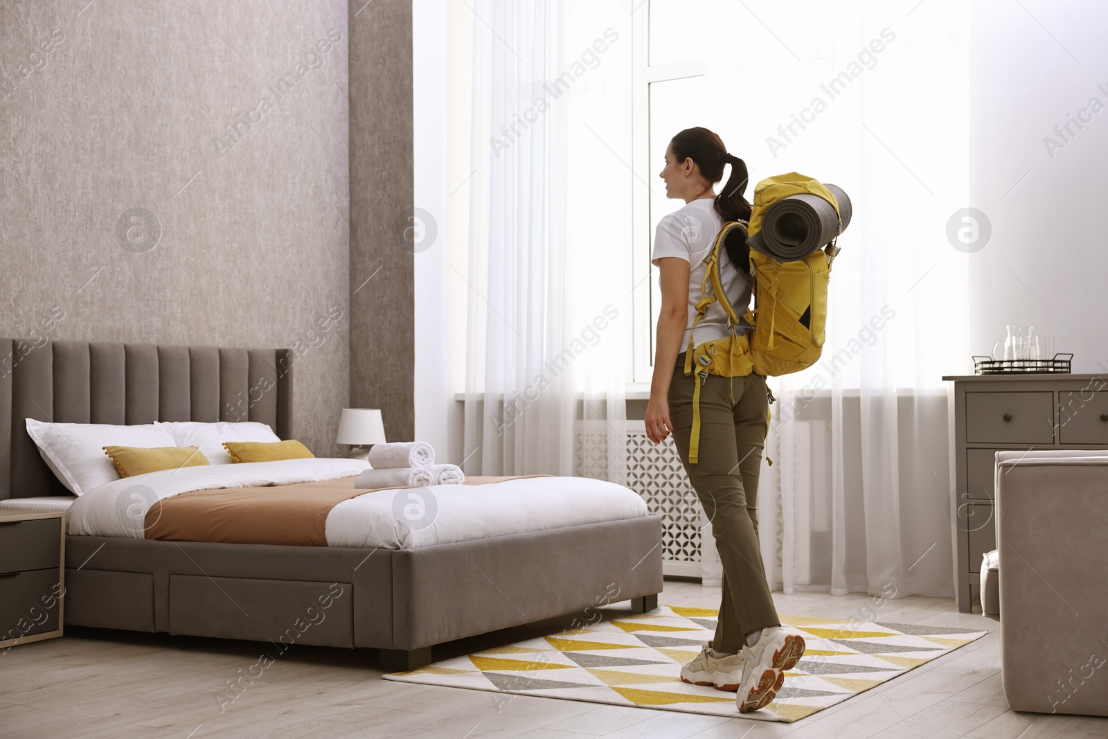 Photo of Traveller with backpack near bed in hotel room