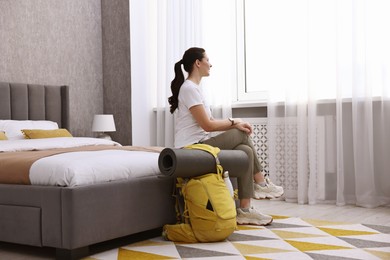 Photo of Traveller with backpack sitting on bed in hotel room