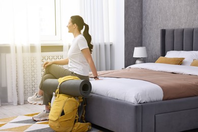 Photo of Traveller with backpack sitting on bed in hotel room