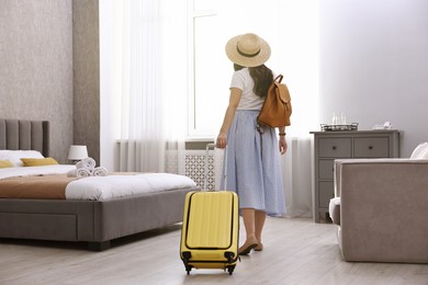 Photo of Traveller with suitcase in hotel room, back view