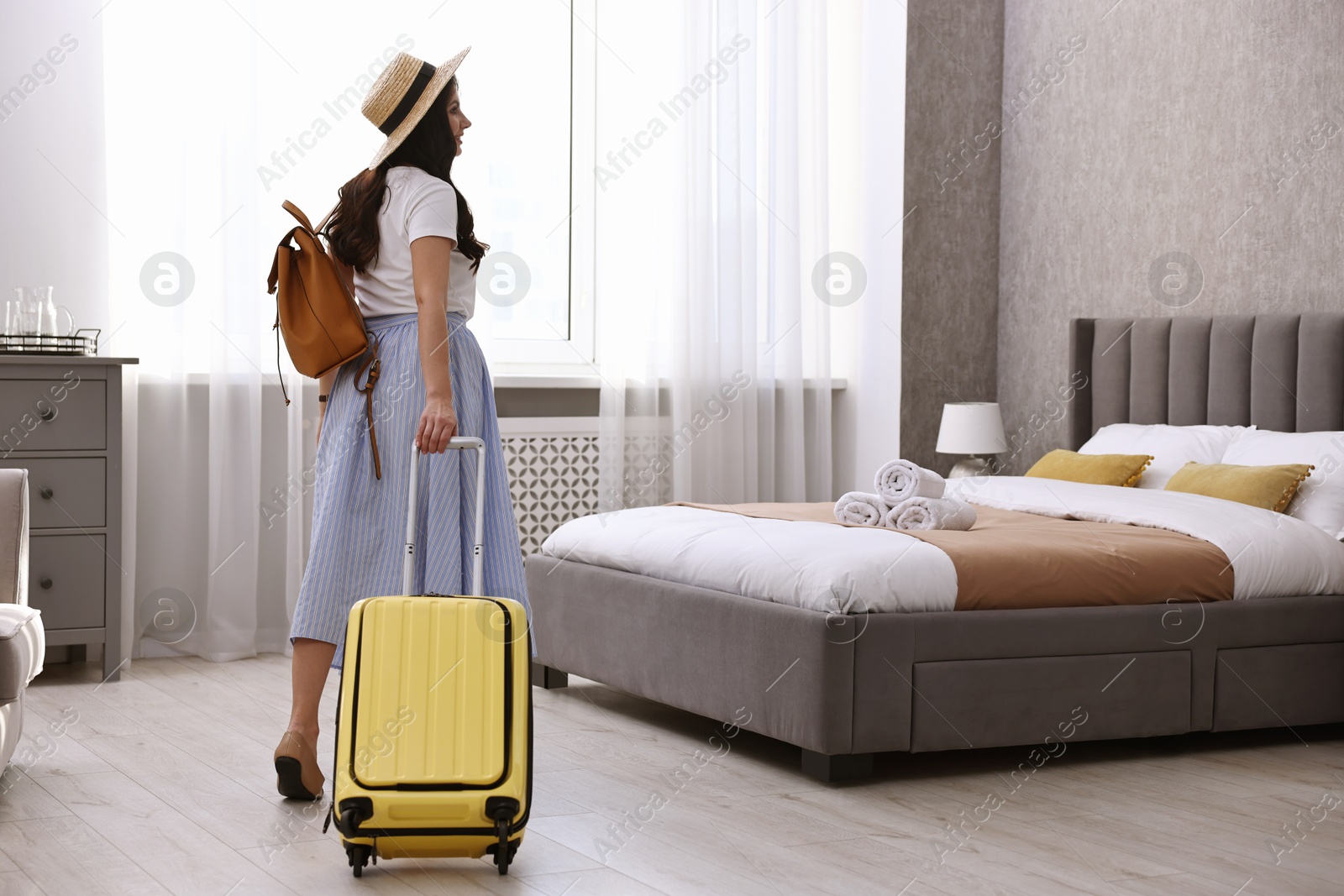 Photo of Traveller with suitcase in hotel room, back view