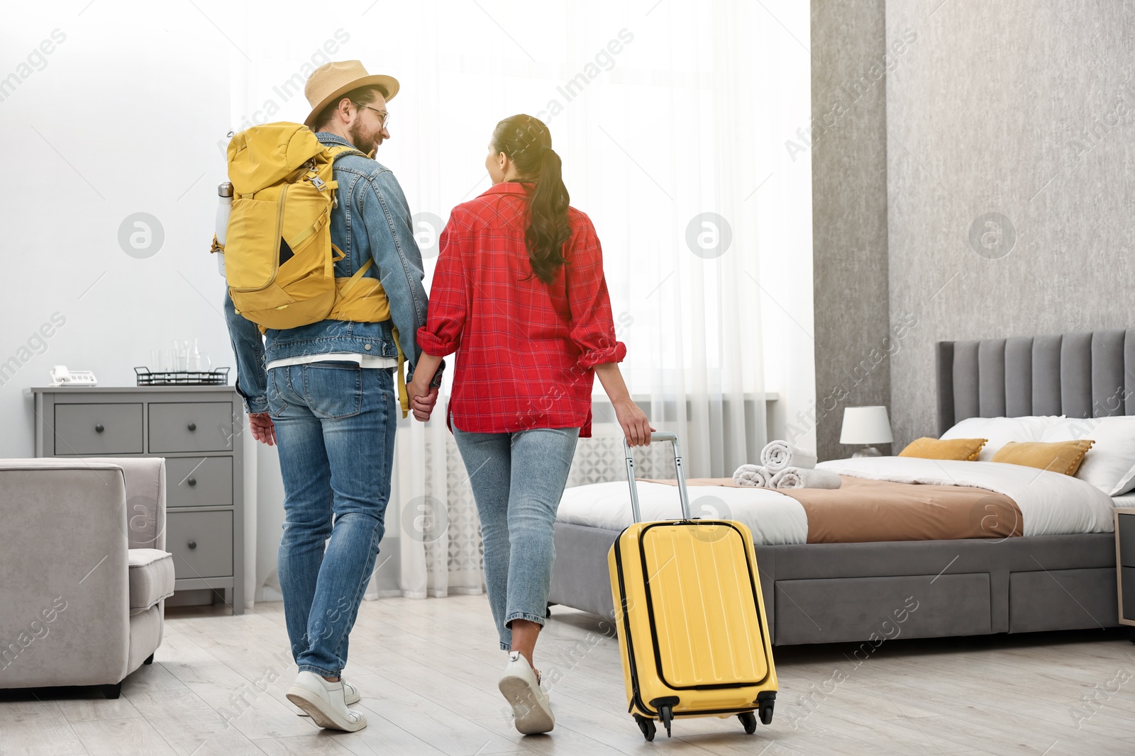 Photo of Travellers with suitcase and backpack in hotel room, back view