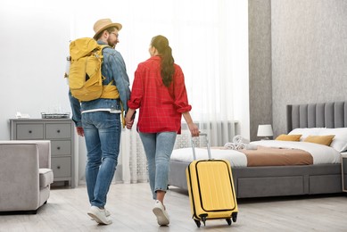 Photo of Travellers with suitcase and backpack in hotel room, back view