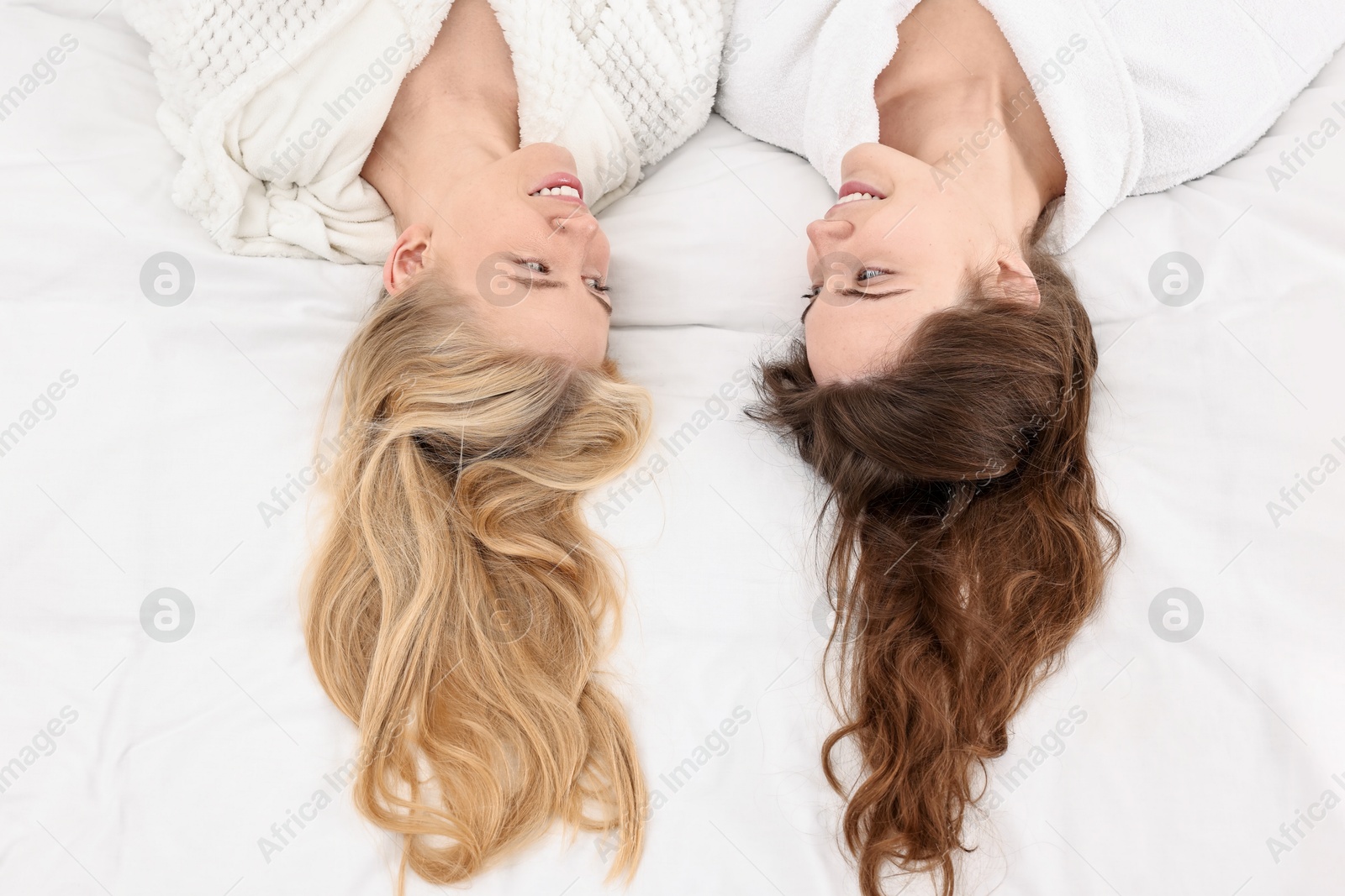 Photo of Spa day. Happy women lying on bed, above view