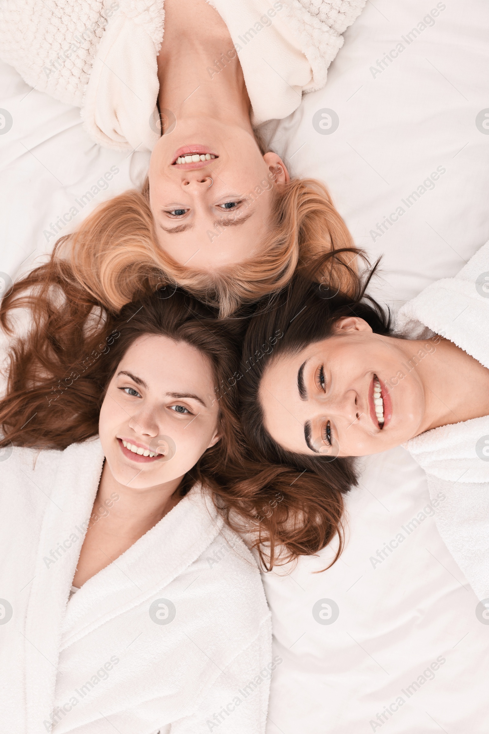 Photo of Spa day. Happy women lying on bed, above view