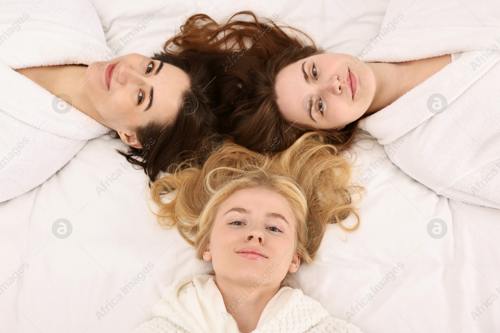 Photo of Spa day. Happy women lying on bed, above view