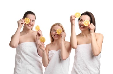 Photo of Spa day. Cheerful women wrapped in towels with orange slices on white background