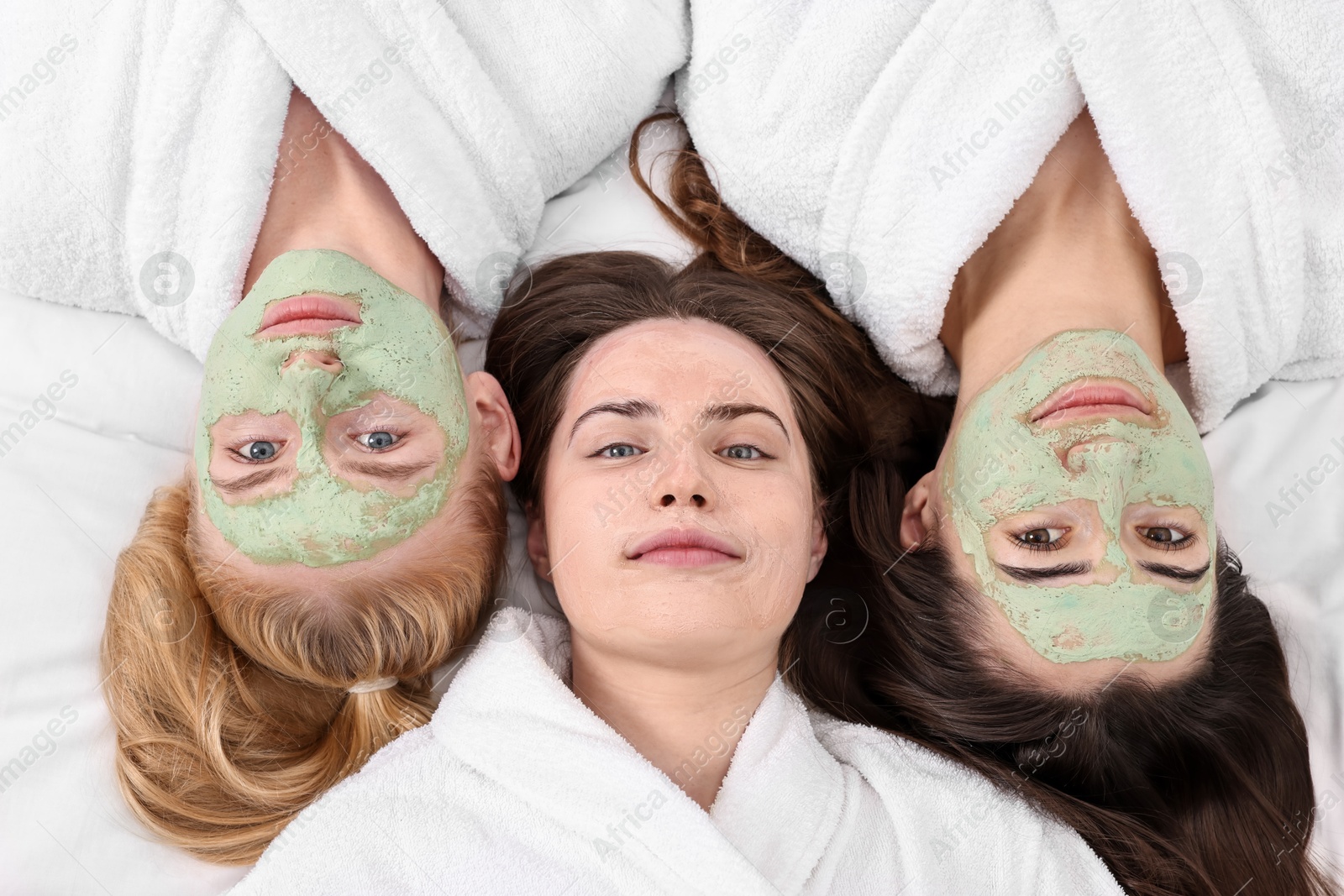 Photo of Spa day. Beautiful woman with face masks on bed, above view