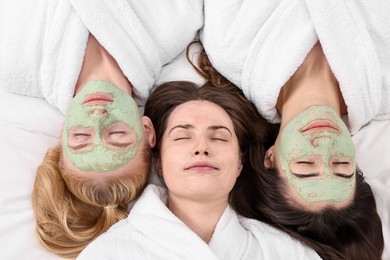 Photo of Spa day. Beautiful woman with face masks on bed, above view