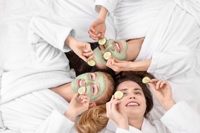 Photo of Spa day. Beautiful woman with face masks and cucumber slices on bed, above view