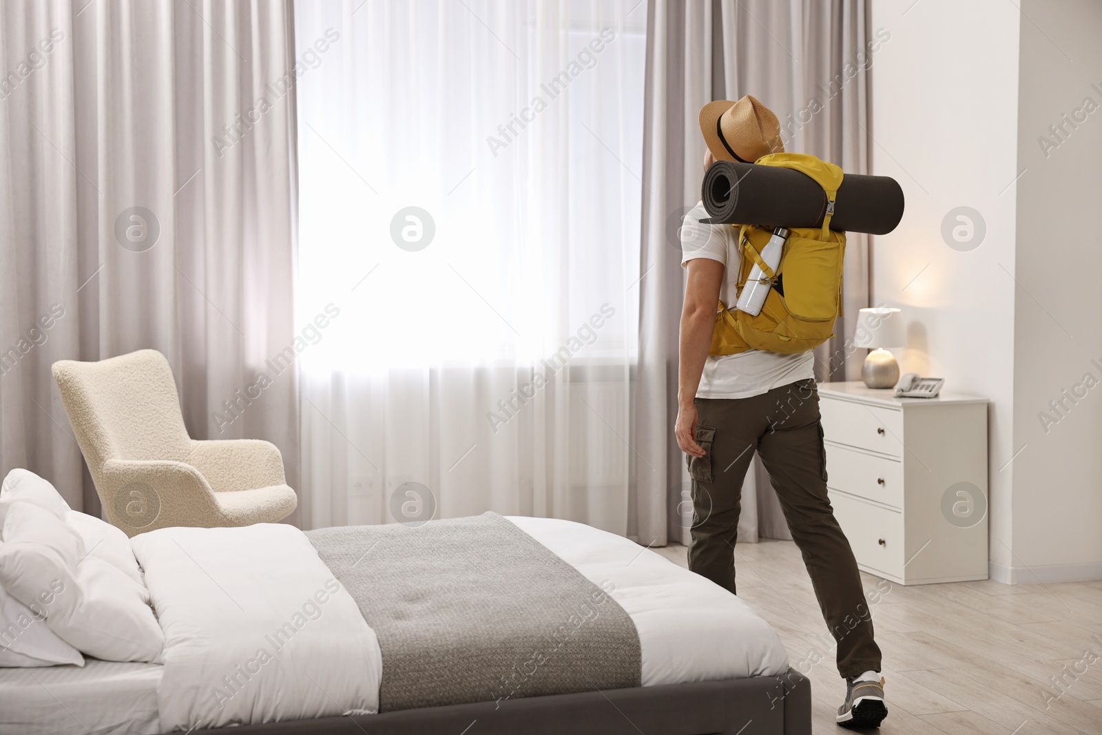 Photo of Traveller with backpack in hotel room, back view