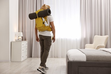 Traveller with backpack in hotel room, back view