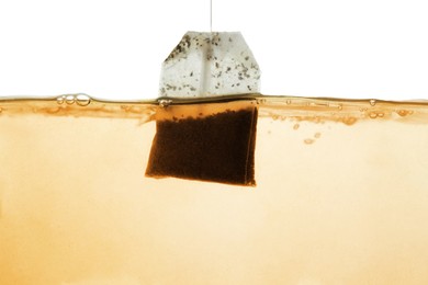 Photo of Putting tea bag into glass cup on white background, closeup