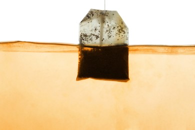 Photo of Putting tea bag into glass cup on white background, closeup