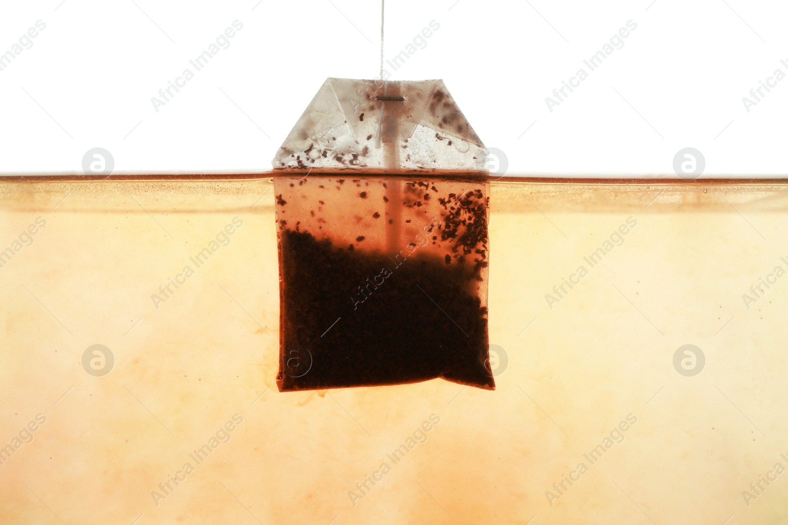 Photo of Putting tea bag into glass cup on white background, closeup