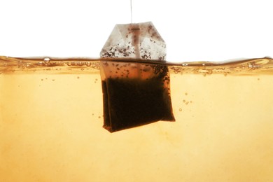 Photo of Putting tea bag into glass cup on white background, closeup