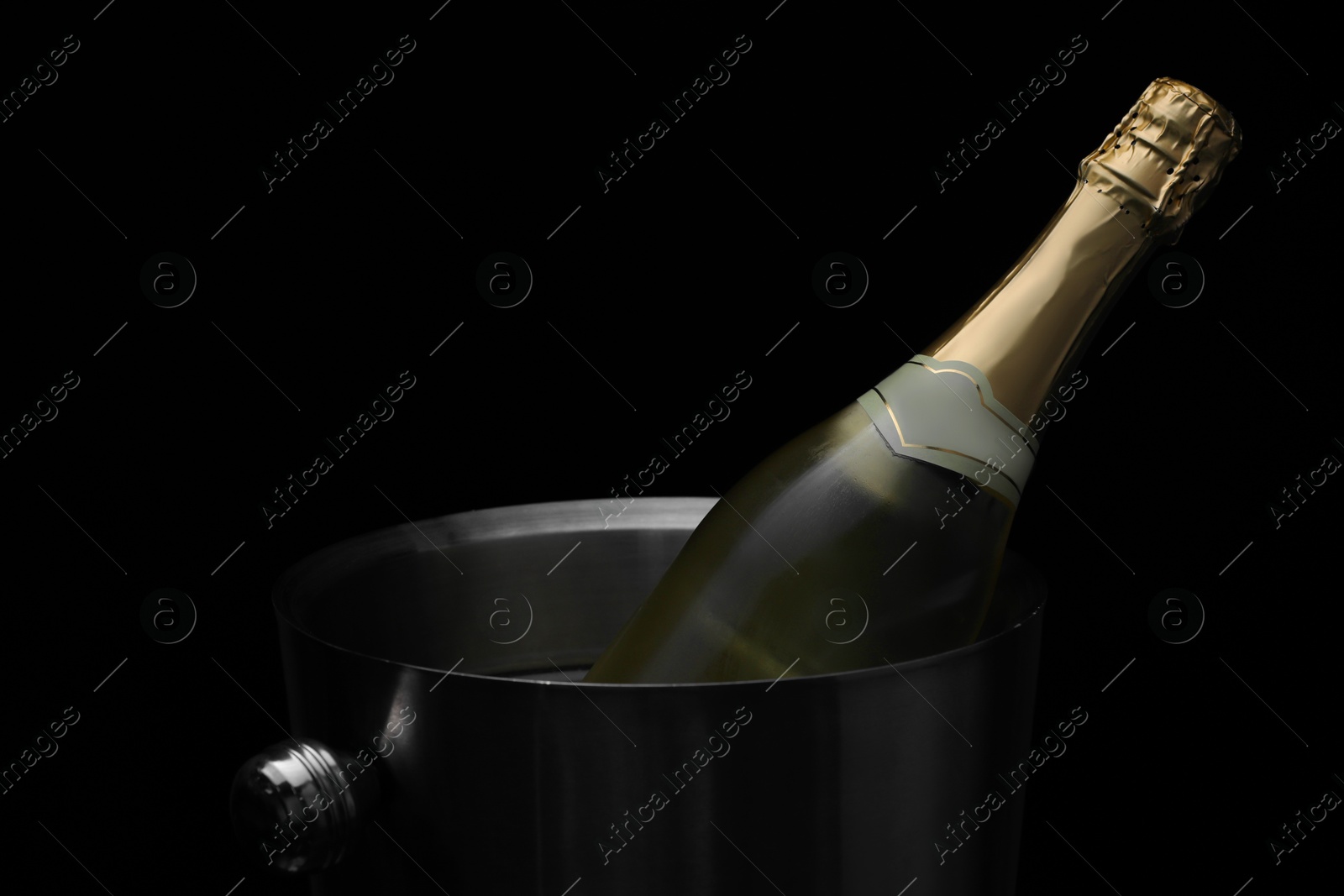 Photo of Bottle of champagne in bucket on black background