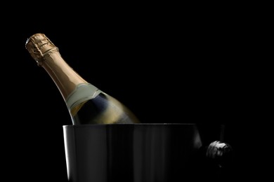 Photo of Bottle of champagne in bucket on black background