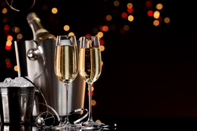 Photo of Champagne in glasses, bottle and ice buckets on mirror surface against color background with blurred lights, space for text