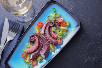 Photo of Tasty boiled octopus tentacles and salad served on grey textured table, flat lay