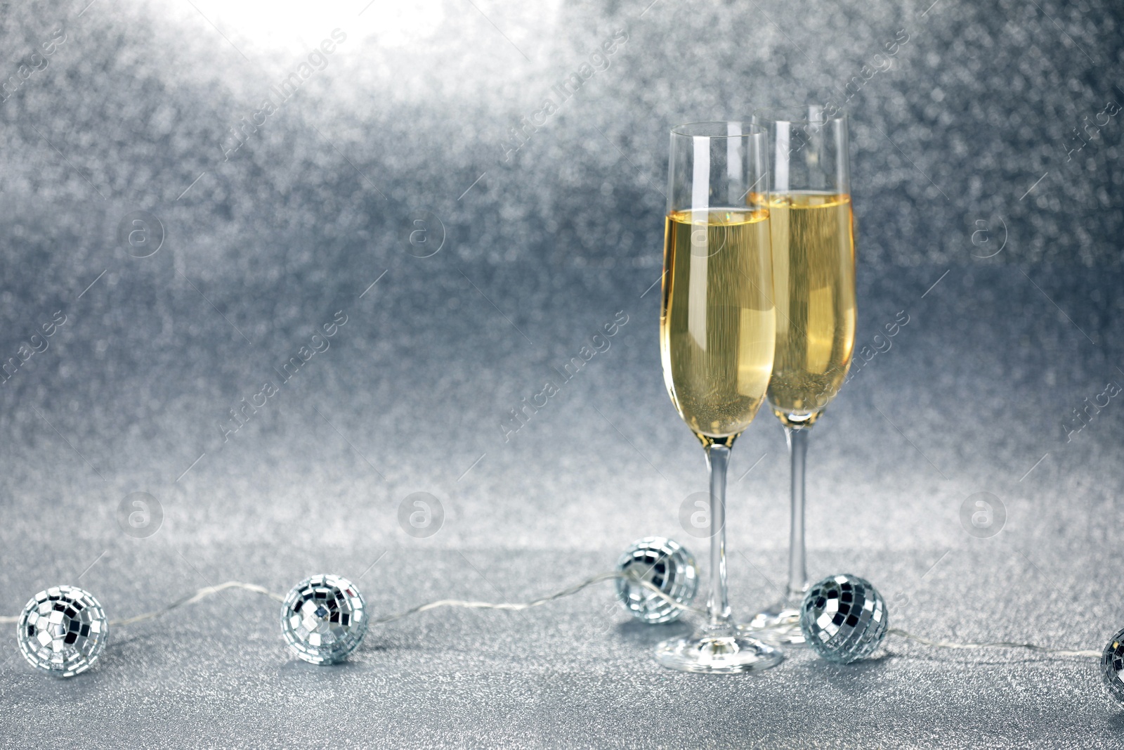 Photo of Champagne in glasses and decor on silver background. Space for text