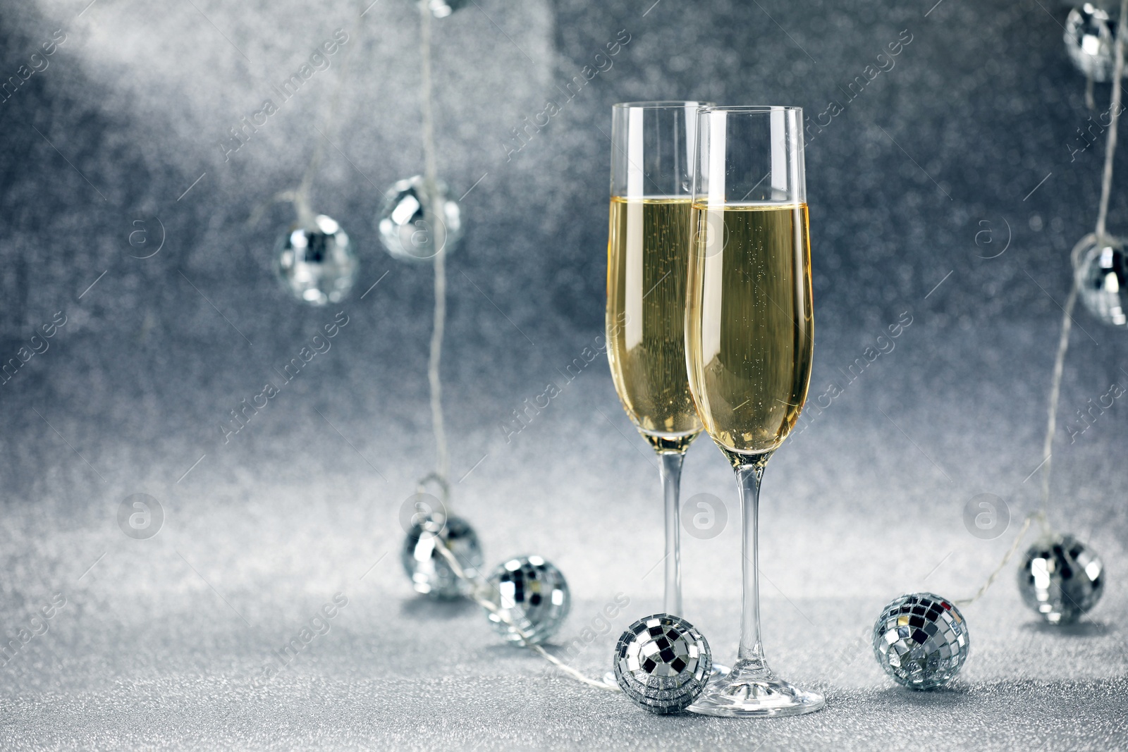 Photo of Champagne in glasses and decor on silver background. Space for text