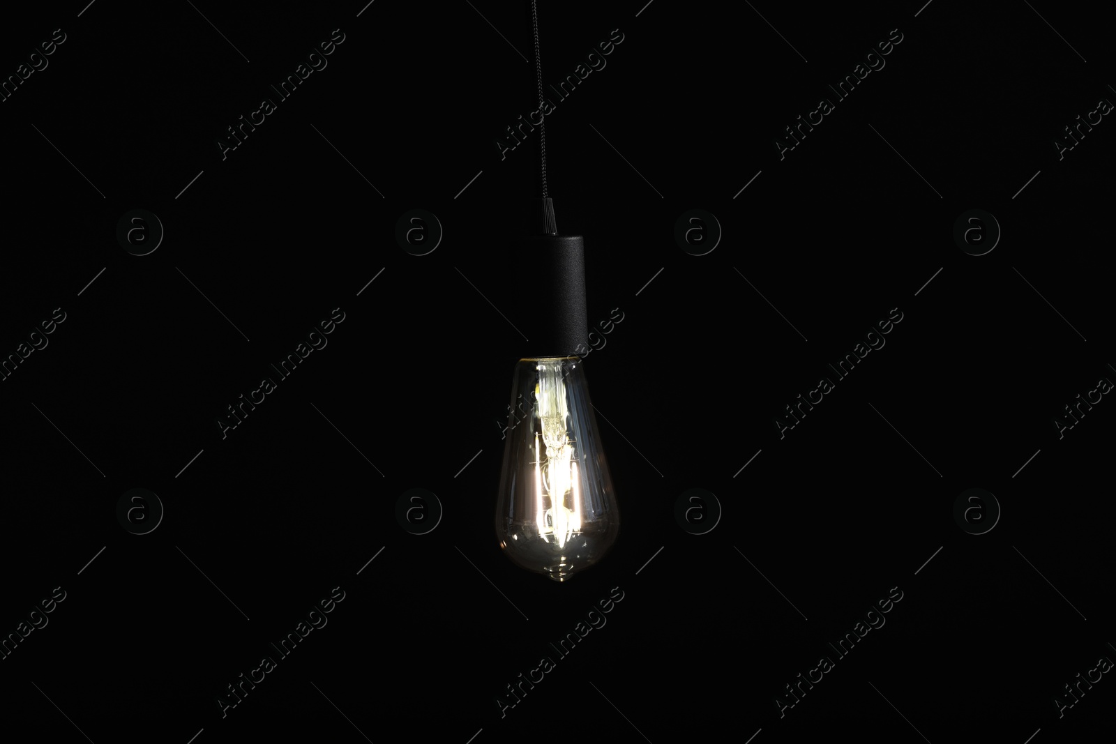 Photo of Glowing light bulb hanging on dark background