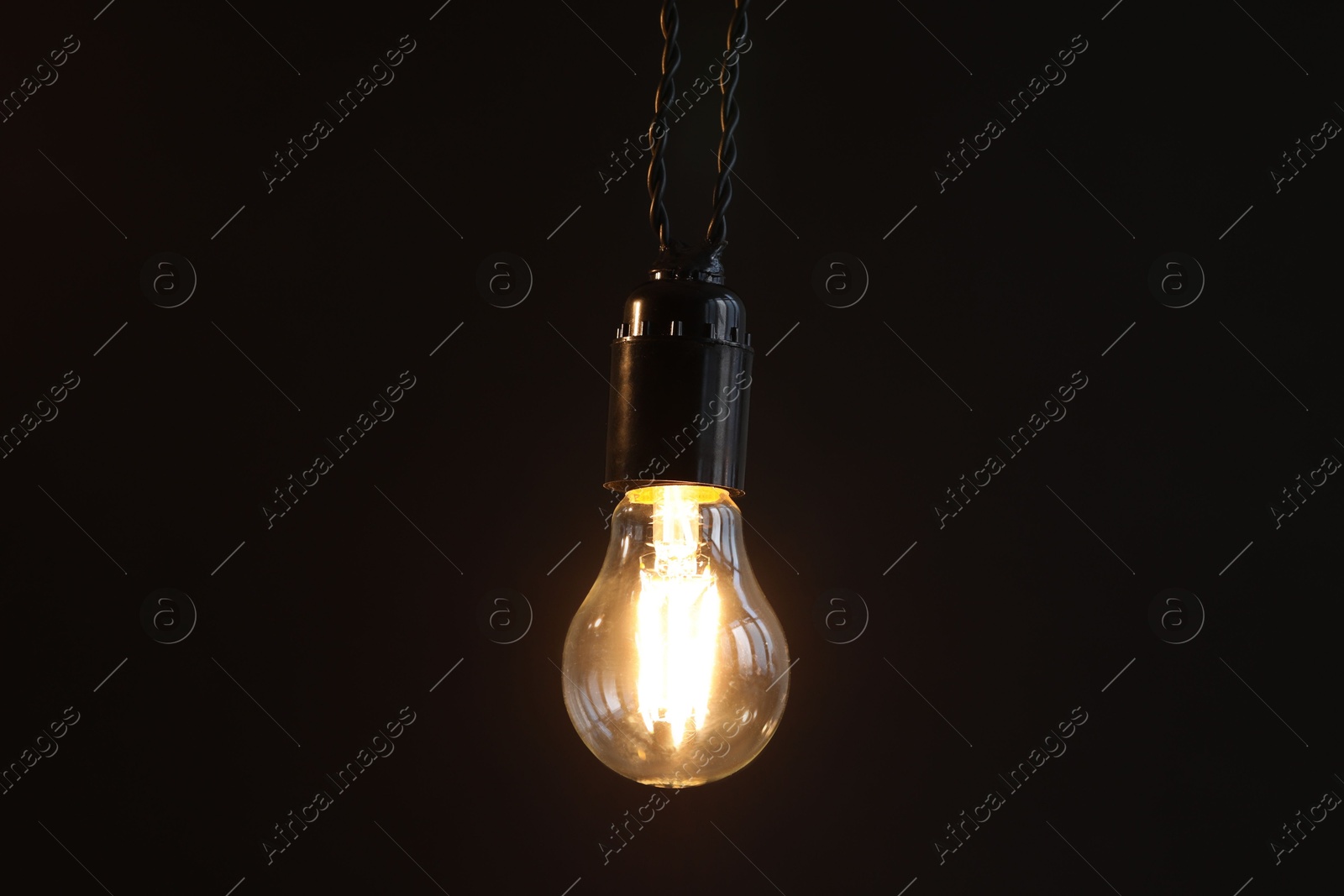 Photo of Glowing light bulb hanging on dark background