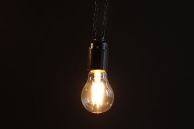 Photo of Glowing light bulb hanging on dark background