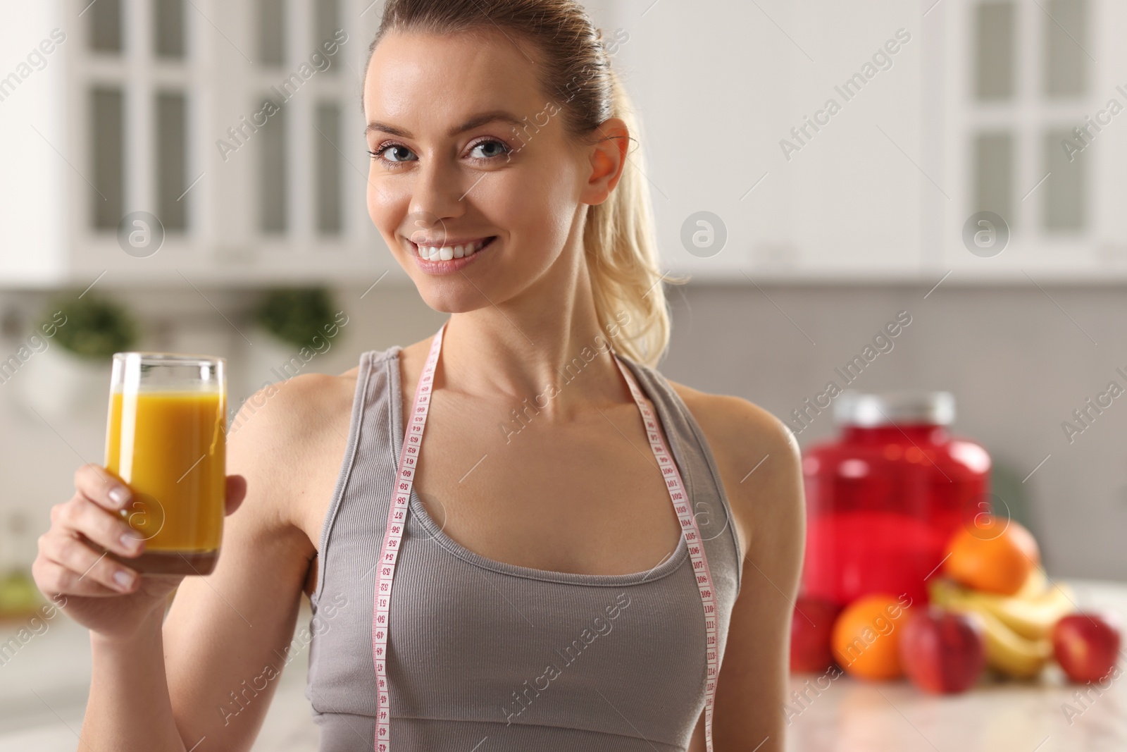 Photo of Weight loss. Happy woman with tasty shake and measuring tape in kitchen, space for text