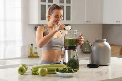 Photo of Weight loss. Happy woman making protein shake at table in kitchen