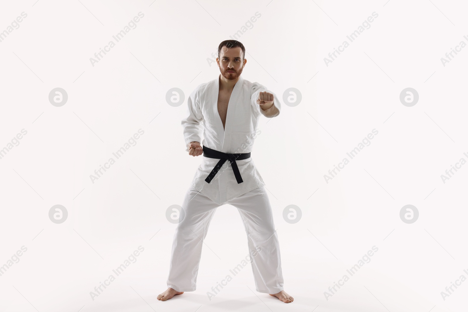 Photo of Man wearing uniform practicing karate on white background