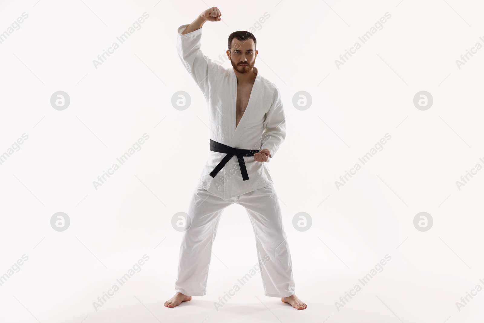 Photo of Man wearing uniform practicing karate on white background