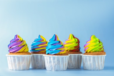 Photo of Tasty cupcakes with colorful cream on light background