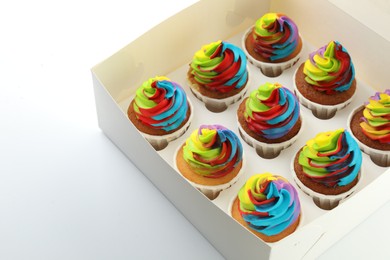 Photo of Tasty cupcakes with colorful cream in box on white background