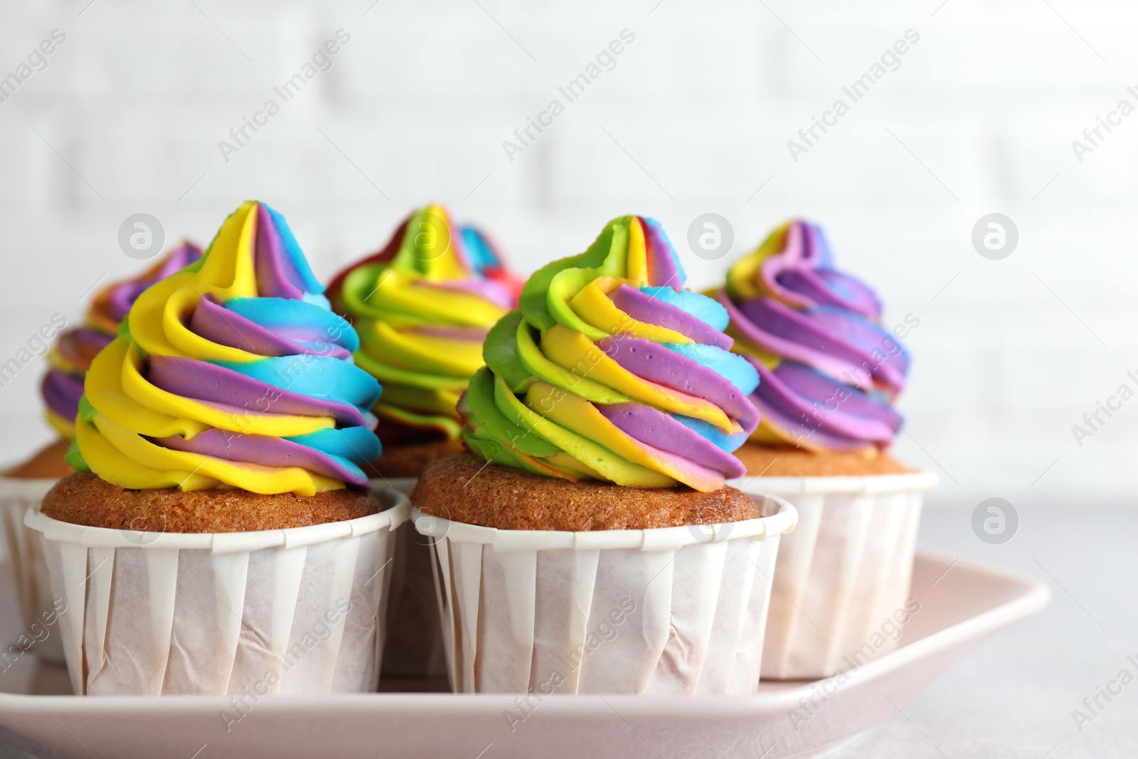 Photo of Tasty cupcakes with colorful cream on light grey table, closeup