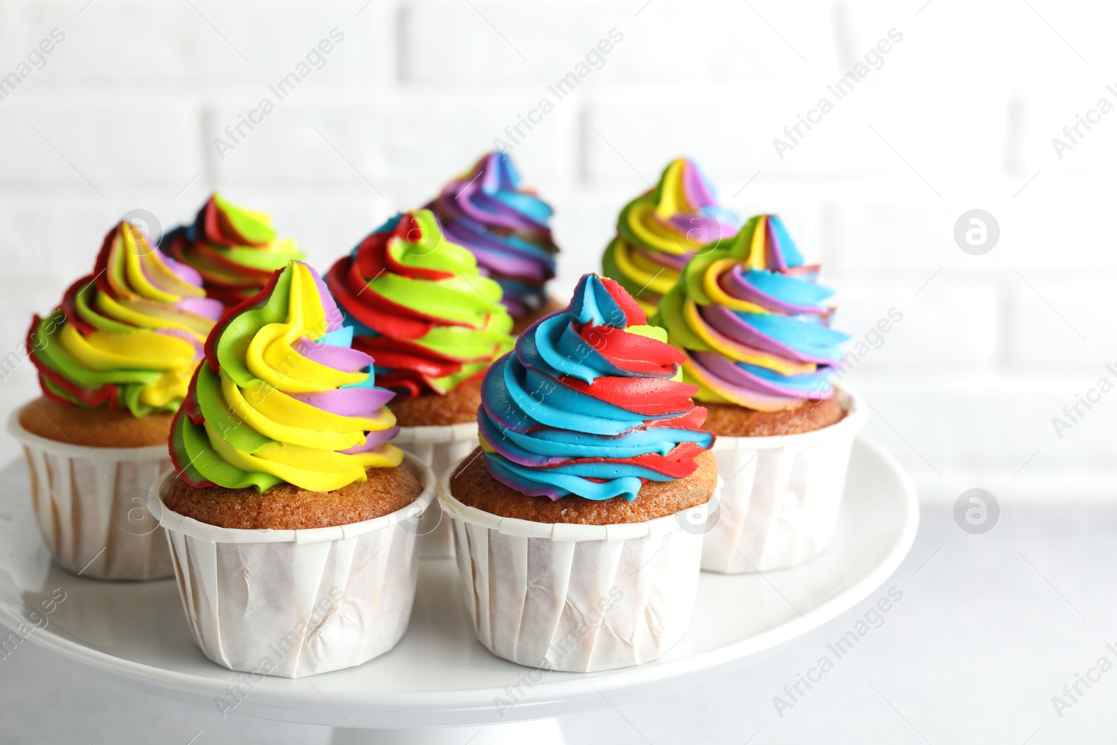 Photo of Tasty cupcakes with colorful cream on white table, closeup