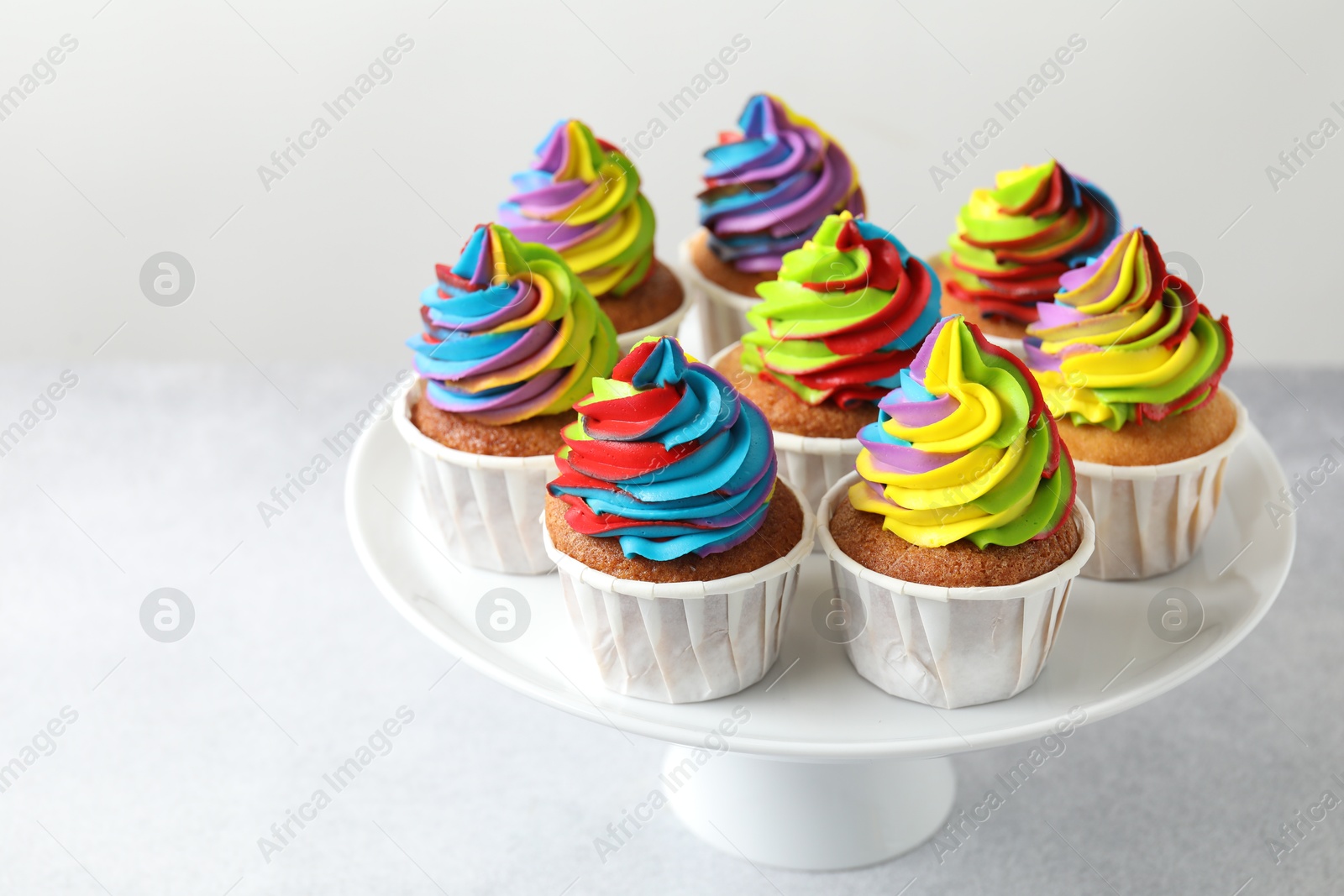 Photo of Tasty cupcakes with colorful cream on white table. Space for text