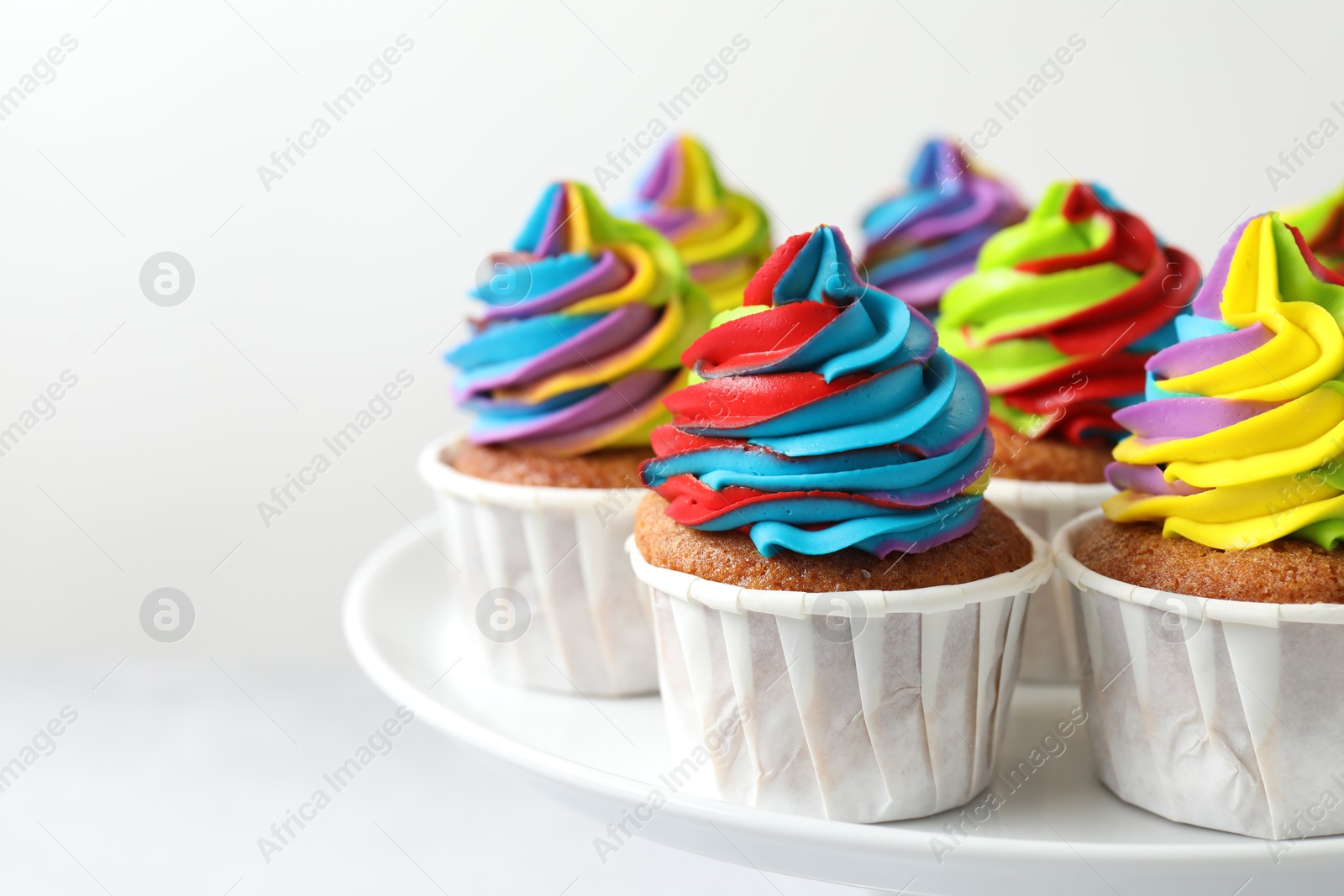 Photo of Tasty cupcakes with colorful cream on white background, closeup. Space for text