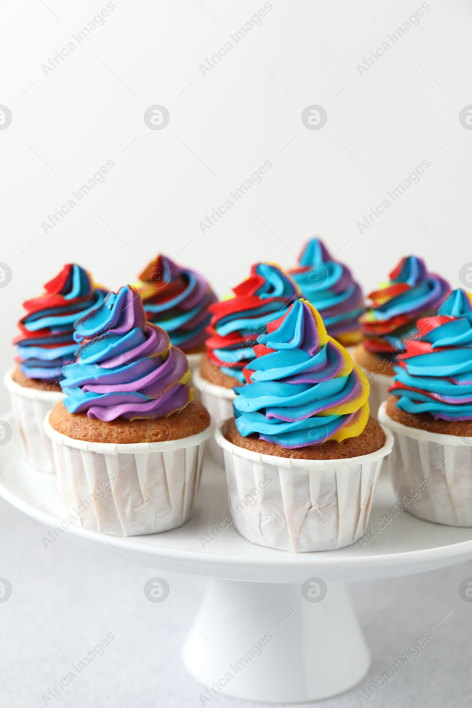 Photo of Tasty cupcakes with colorful cream on white table, closeup