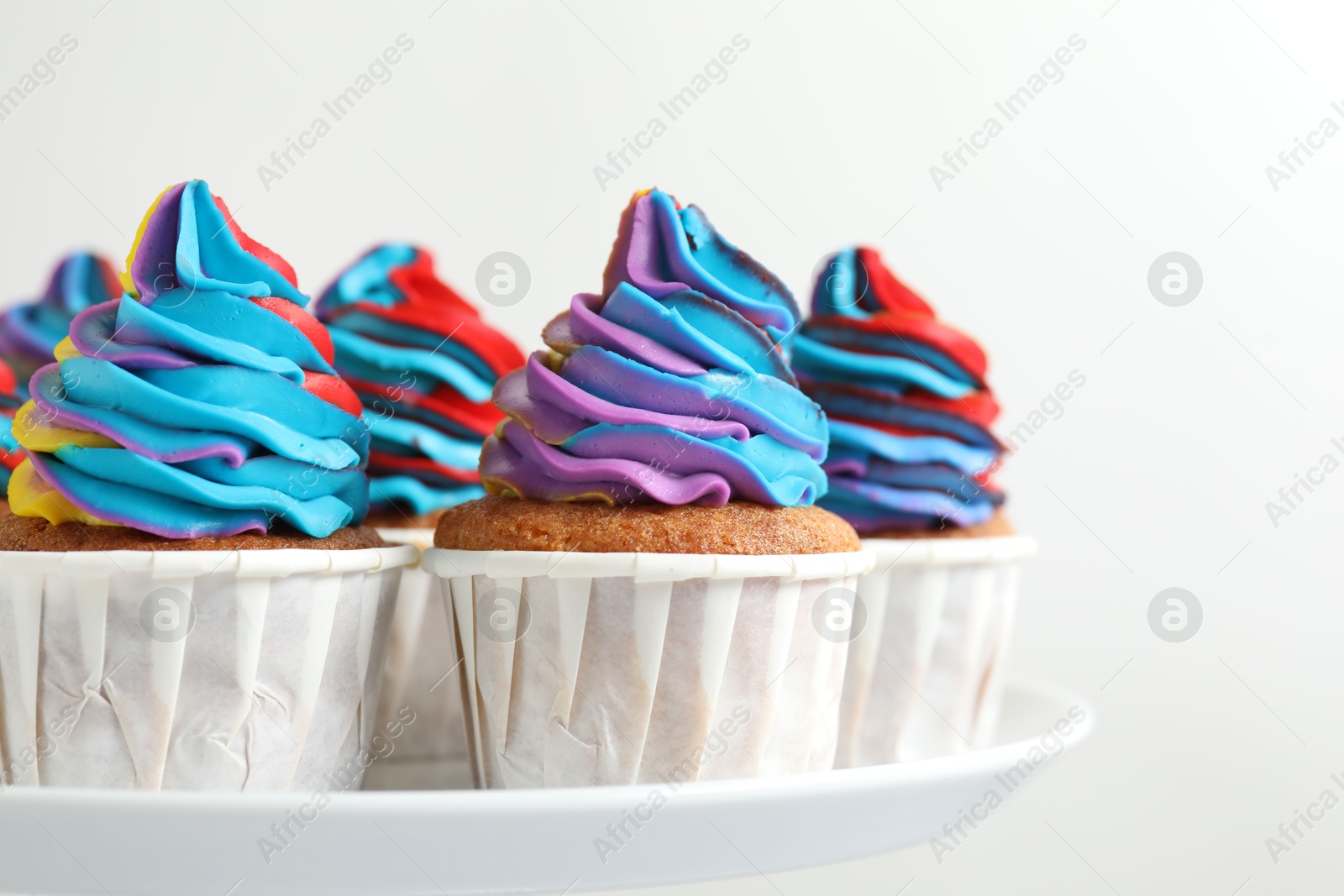 Photo of Tasty cupcakes with colorful cream on white background, closeup