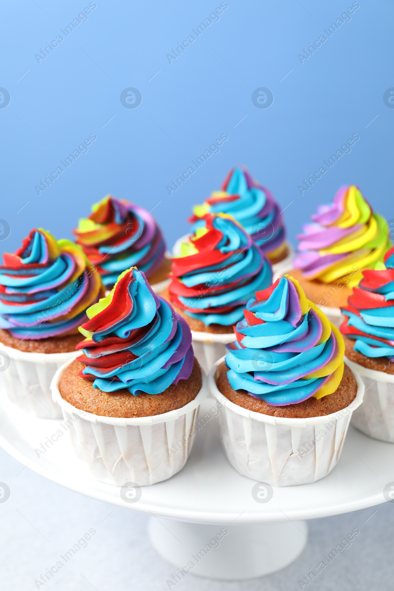 Photo of Tasty cupcakes with colorful cream on white table, closeup