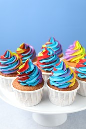 Photo of Tasty cupcakes with colorful cream on white table, closeup