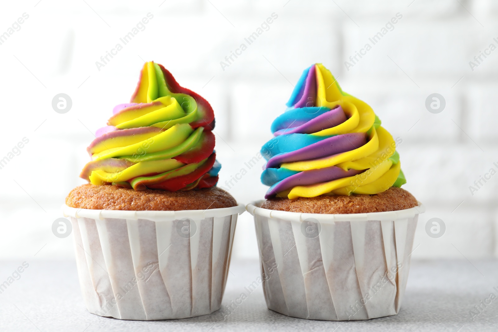 Photo of Tasty cupcakes with colorful cream on white table, closeup